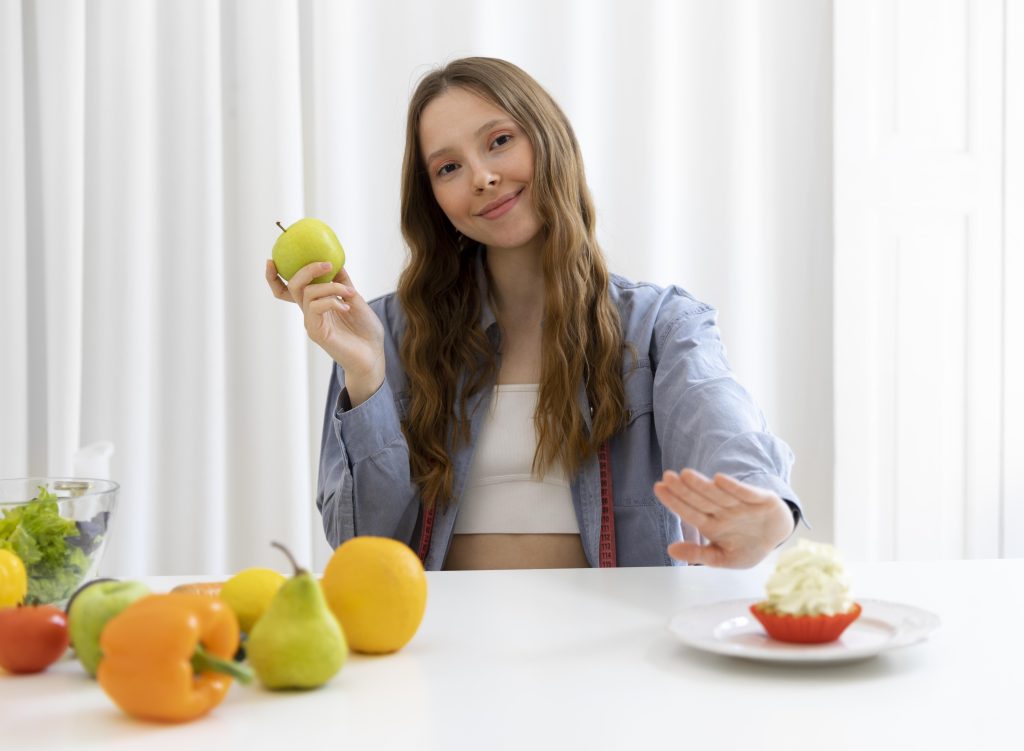 Imagen de una mujer eligiendo una manzana en lugar de un dulce, esto le ayuda a fortalecer su estómago.